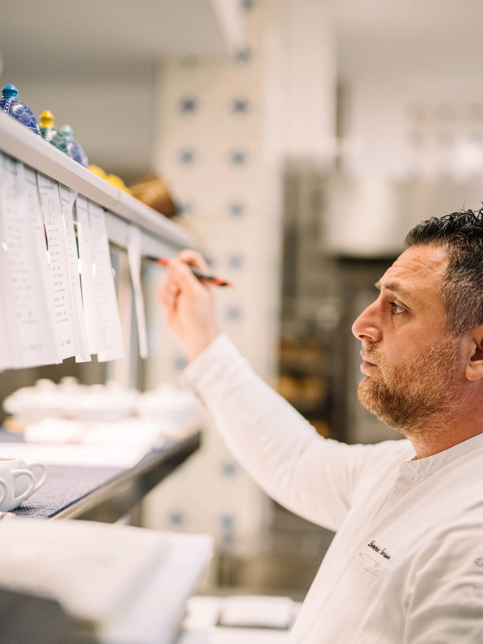 Una persona in cucina scrive su fogli appesi